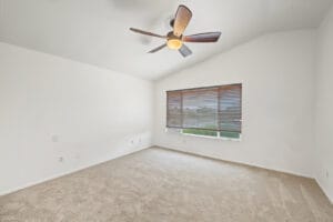 Bedroom with vaulted ceiling, ceiling fan, large window and new carpet