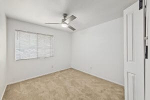 Carpeted bedroom with brushed nickel ceiling fan and window blinds