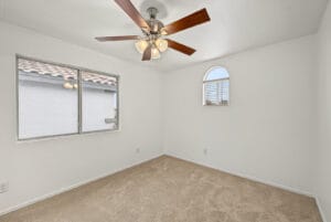 Upstairs bedroom with arched window, ceiling fan and carpet