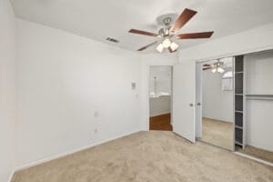Bedroom with mirrored sliding closet doors and five-blade ceiling fan