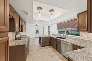 Kitchen with granite counters, dark wood cabinets and stainless dishwasher, open to the dining area