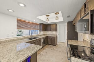 Kitchen with granite countertops, stacked-stone backsplash and pendant lights