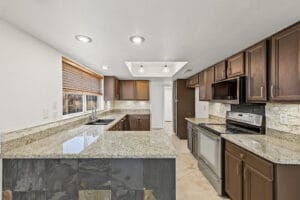 Kitchen with granite peninsula, slate-tile accent and stainless range and microwave