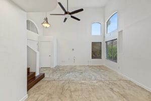 Two-story living room with ceiling fan, arched clerestory windows and stained concrete floors