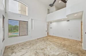 Living room with high ceilings and a pool-view window, overlooked by the upstairs loft