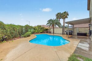 Private pool with palm trees, covered patio and grill area in a Glendale, AZ backyard