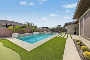 Self-cleaning heated pool with putting green and covered patio at 1255 E Mead Dr, Gilbert, AZ