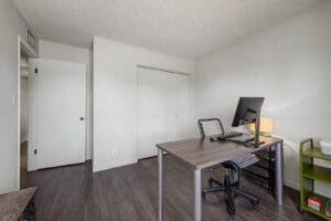 Bedroom with double closet doors, wood-look flooring, and hallway entry door