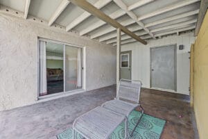 Covered back patio with sliding glass door to the living room and exterior storage door