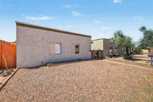 Angled front view of Tempe home with modern flat roofline, gravel front yard, and walkway to courtyard gate