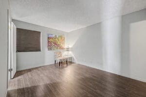 Bedroom with wood-look flooring, neutral gray walls, and window with cellular shade