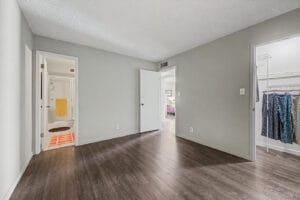 Primary bedroom with wood-look flooring, private bathroom, and walk-in closet with wire shelving