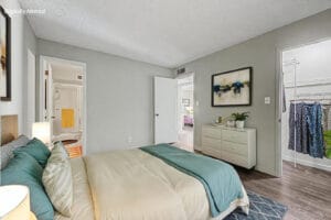 Virtually staged primary bedroom with queen bed and dresser, showing the bathroom and walk-in closet