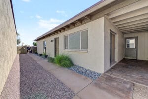 Side courtyard with concrete walkway, river rock border, ornamental grass, and patio slide