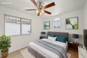 Virtually staged bedroom with arched window, gray tufted bed and wall art