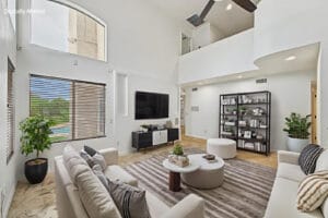 Virtually staged living room with sofas and pool-view window beneath the upstairs loft