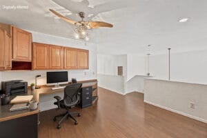 Loft office virtually staged with desk chair and computer, overlooking the living room