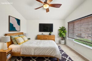 Virtually staged bedroom with vaulted ceiling, bed, dresser and wall-mounted TV