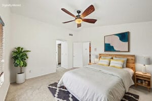 Virtually staged primary bedroom with queen bed, vaulted ceiling and walk-in closet entry