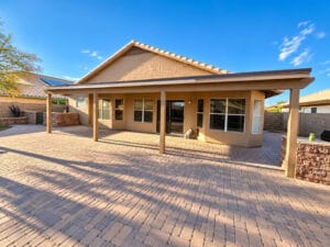 Back of home with extended covered patio, paver hardscape and built-in stone BBQ counter