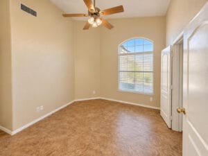 Den with vaulted ceiling, arched window, ceiling fan and double-door entry