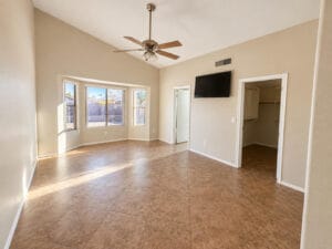 Primary bedroom with vaulted ceiling, bay window, ceiling fan and walk-in closet