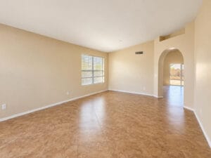 Formal living room with tile floors and arched doorway opening to the family room