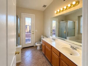 Primary bathroom with dual-sink vanity, walk-in shower and private door to the backyard