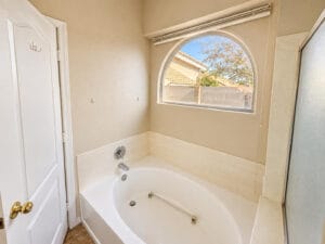 Primary bathroom soaking tub beneath an arched window